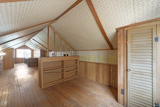 additional living space featuring lofted ceiling, wood walls, hardwood / wood-style floors, and wainscoting