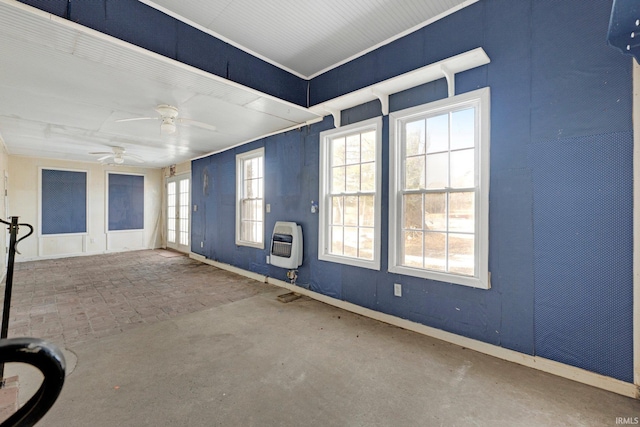 empty room featuring heating unit, plenty of natural light, baseboards, and ceiling fan