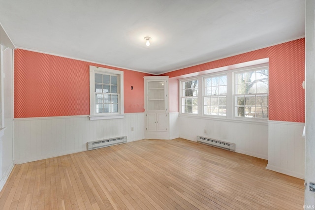 spare room featuring a baseboard heating unit, a wainscoted wall, and hardwood / wood-style floors