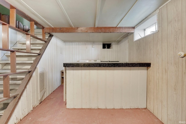 bar with a dry bar, wood walls, and stairway