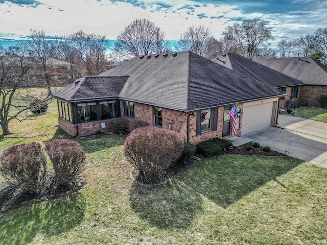 ranch-style house featuring a garage, brick siding, concrete driveway, roof with shingles, and a front lawn