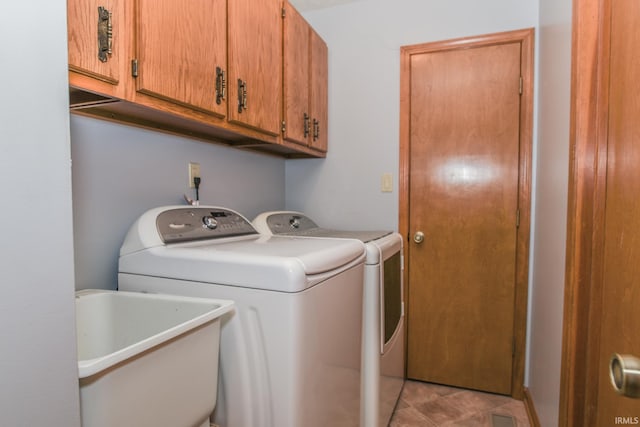 clothes washing area with washing machine and dryer, cabinet space, and a sink