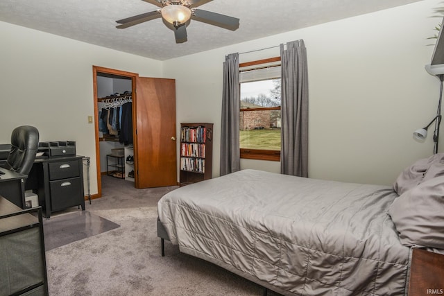 carpeted bedroom featuring a textured ceiling, a spacious closet, a closet, and ceiling fan