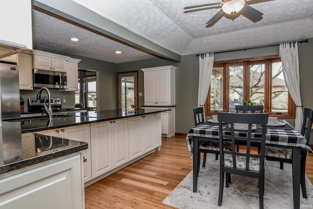 kitchen featuring appliances with stainless steel finishes, a healthy amount of sunlight, white cabinets, and light wood-style flooring