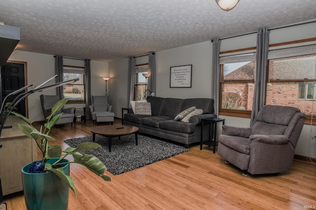 living area with a wealth of natural light, a textured ceiling, and wood finished floors