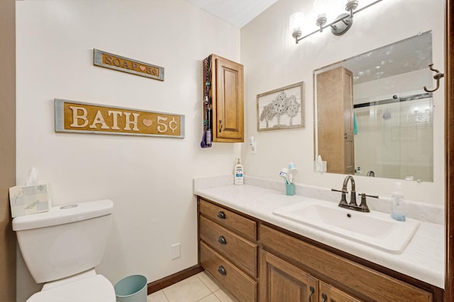 bathroom featuring a shower with shower door, toilet, vanity, baseboards, and tile patterned floors