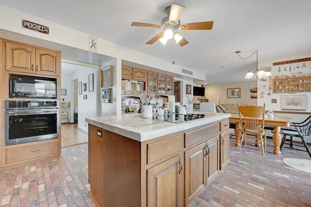 kitchen featuring brick floor, light countertops, a kitchen island, and black appliances