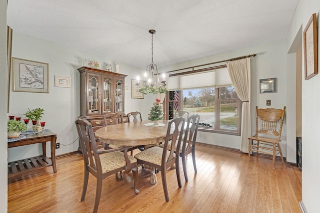 dining room featuring baseboards, light wood-type flooring, and an inviting chandelier