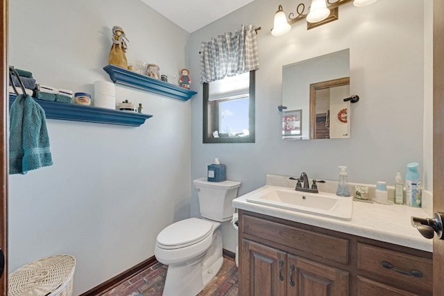 half bath featuring toilet, brick floor, baseboards, and vanity