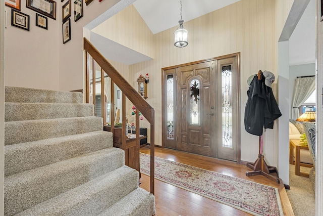 foyer entrance with high vaulted ceiling, baseboards, stairs, light wood-style floors, and wallpapered walls