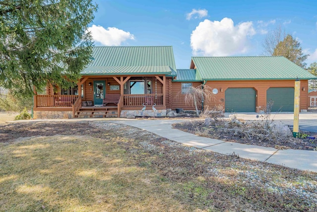 chalet / cabin featuring an attached garage, metal roof, a porch, and concrete driveway