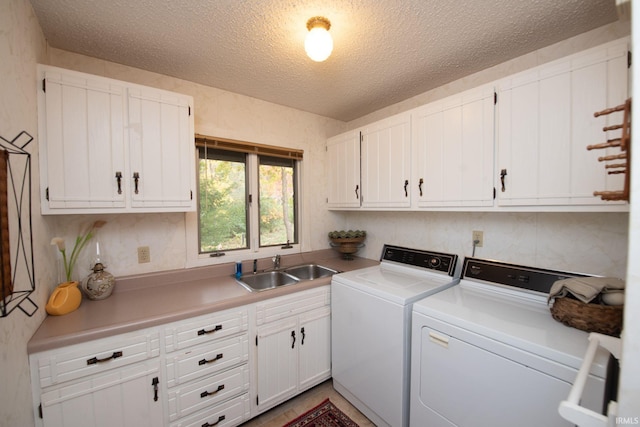 washroom featuring a textured ceiling, separate washer and dryer, a sink, and cabinet space