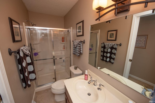 full bathroom with toilet, a shower stall, a textured ceiling, vanity, and baseboards