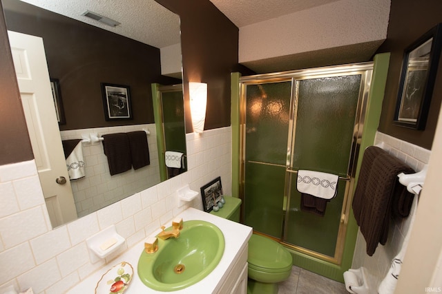 bathroom with visible vents, a textured ceiling, a shower stall, and vanity