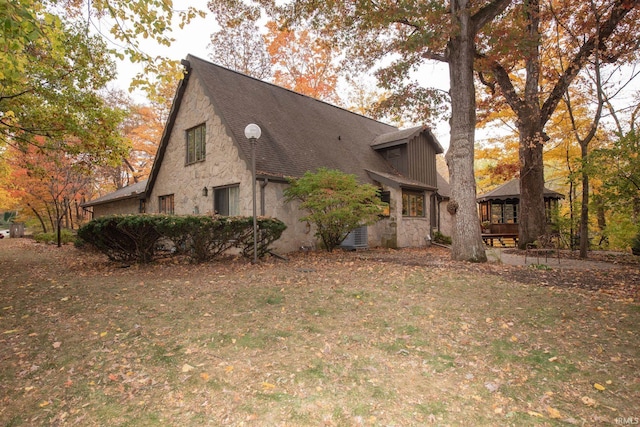 view of side of home featuring stone siding and a gazebo