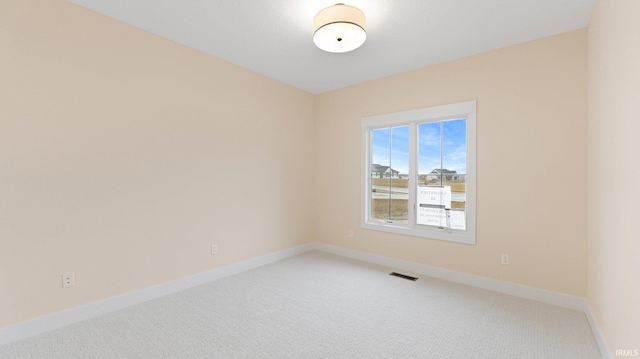 spare room featuring light carpet, visible vents, and baseboards