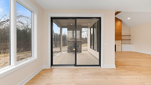 doorway featuring lofted ceiling, baseboards, wood finished floors, and recessed lighting