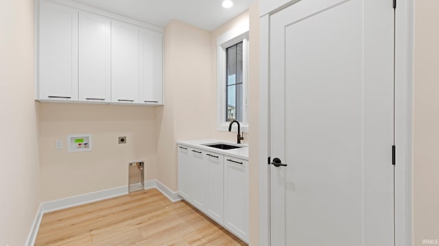 laundry area featuring cabinet space, a sink, electric dryer hookup, light wood-type flooring, and baseboards