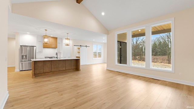 kitchen with light countertops, a barn door, light wood-style floors, and stainless steel fridge with ice dispenser