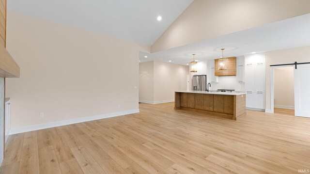 kitchen with light countertops, a barn door, light wood-type flooring, and stainless steel fridge with ice dispenser