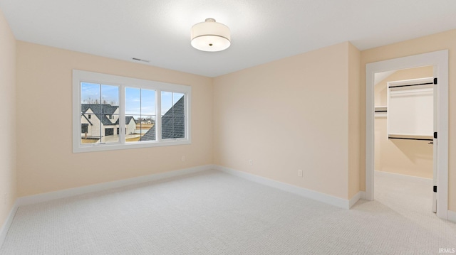 unfurnished bedroom featuring a walk in closet, a closet, visible vents, carpet flooring, and baseboards