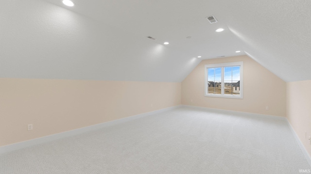 bonus room with lofted ceiling, light colored carpet, visible vents, and baseboards