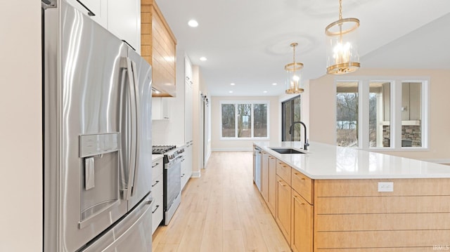 kitchen with light wood-style flooring, recessed lighting, a sink, appliances with stainless steel finishes, and a center island with sink