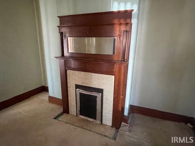 interior details with baseboards and a tile fireplace