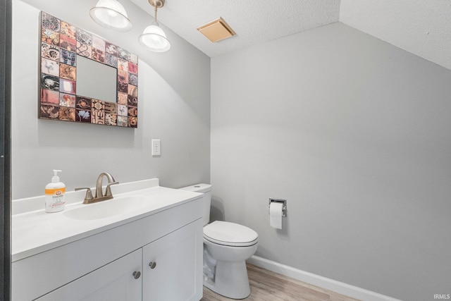 bathroom with baseboards, toilet, wood finished floors, a textured ceiling, and vanity