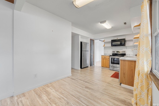 kitchen with light wood-style floors, appliances with stainless steel finishes, open shelves, and a sink