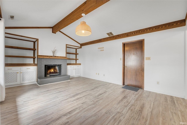 unfurnished living room with vaulted ceiling with beams, a brick fireplace, wood finished floors, and visible vents