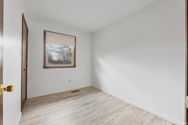 spare room featuring light wood-type flooring, visible vents, and baseboards