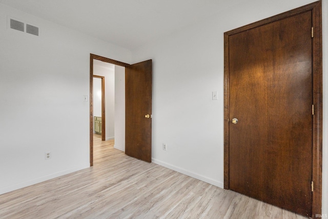 unfurnished bedroom with light wood finished floors, visible vents, and baseboards