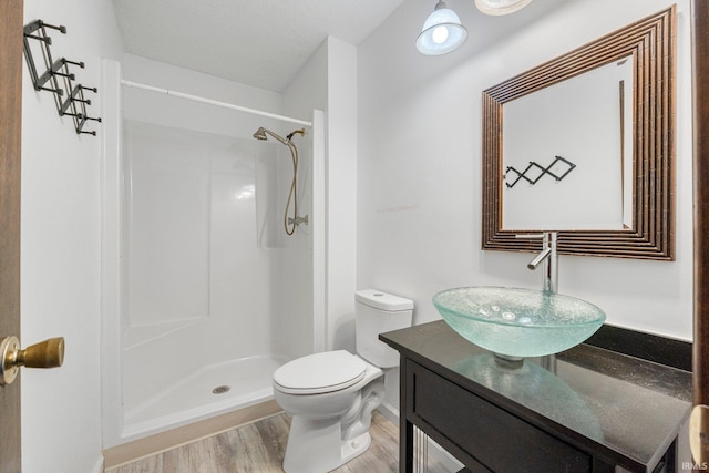 full bathroom with toilet, a stall shower, wood finished floors, and vanity