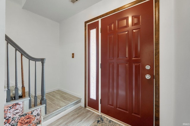 foyer entrance featuring light wood-type flooring, baseboards, and stairs