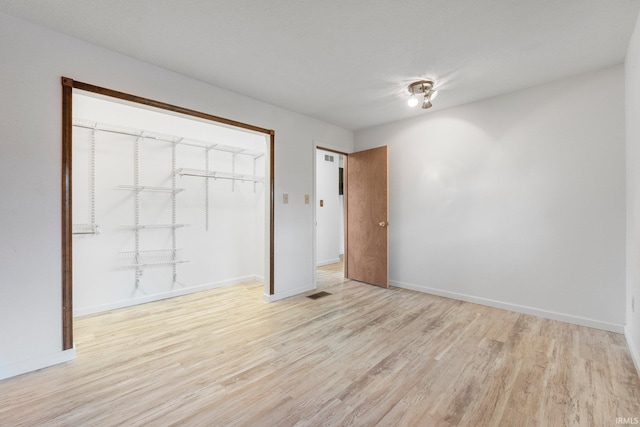 unfurnished bedroom featuring visible vents, a closet, light wood-style flooring, and baseboards