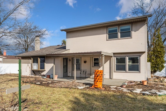 rear view of house featuring a yard, a chimney, fence, and a patio