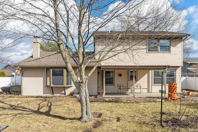 view of front of property with a chimney, a front yard, and fence