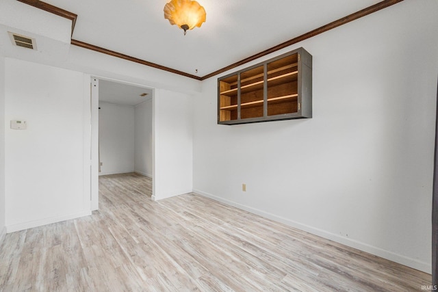 spare room with visible vents, crown molding, baseboards, and wood finished floors