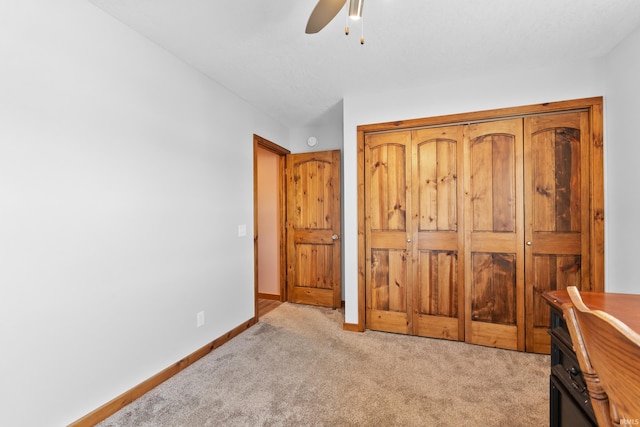 bedroom featuring a ceiling fan, a closet, light colored carpet, and baseboards