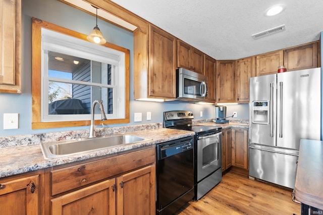 kitchen featuring visible vents, stainless steel appliances, a textured ceiling, light wood-style floors, and a sink