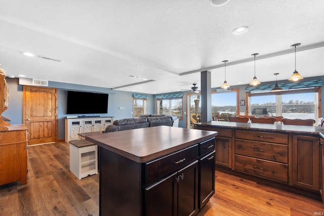 kitchen with open floor plan, wood finished floors, and visible vents