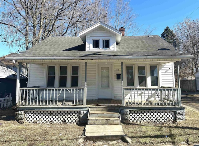 bungalow featuring covered porch, a shingled roof, and a chimney