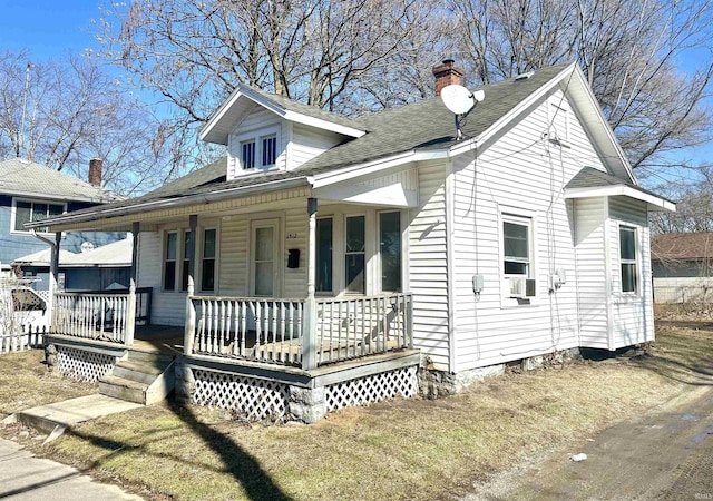 view of front of property featuring a chimney, roof with shingles, fence, cooling unit, and a porch