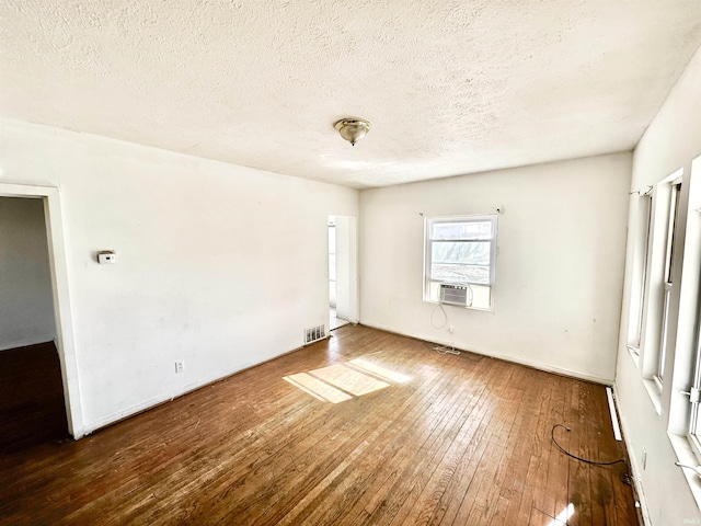 spare room featuring a textured ceiling, hardwood / wood-style floors, cooling unit, and visible vents