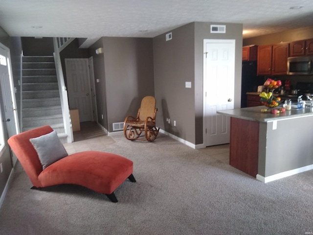 interior space featuring light colored carpet, visible vents, baseboards, brown cabinets, and stainless steel microwave