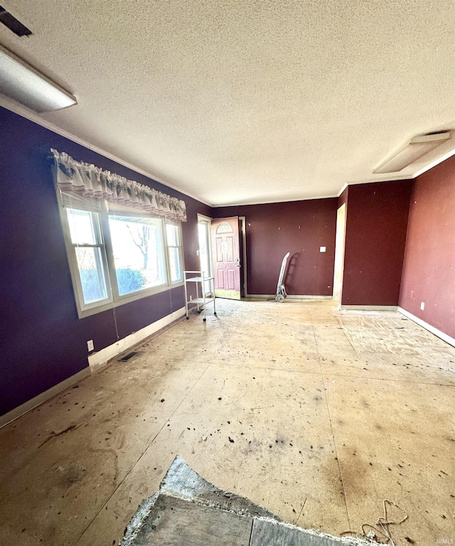 interior space with a textured ceiling, visible vents, and baseboards