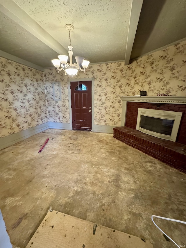 foyer entrance featuring a chandelier, a fireplace, baseboards, and wallpapered walls