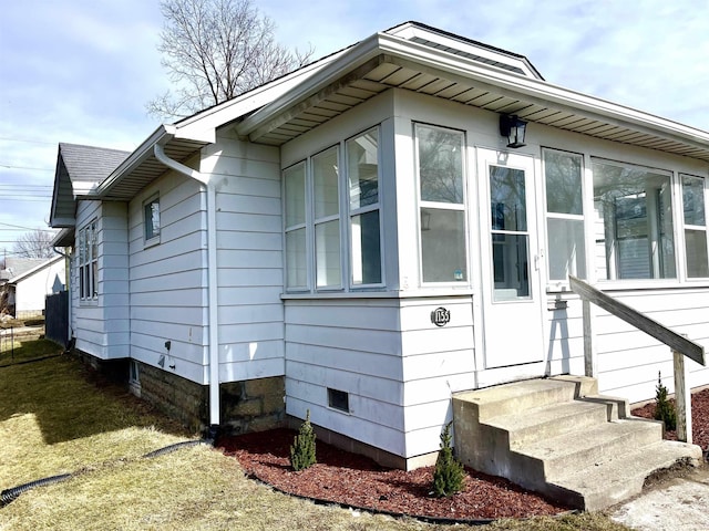 view of side of home featuring a sunroom and a shingled roof