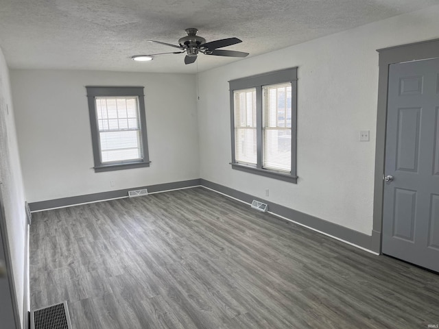 unfurnished room with dark wood finished floors, visible vents, and baseboards